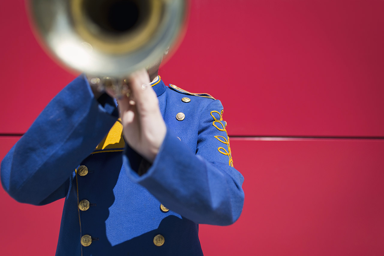 Musician in blue uniform playing trumpet.