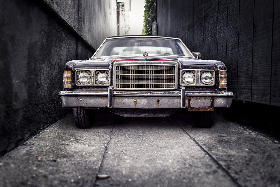 Classic car parked in narrow alleyway.