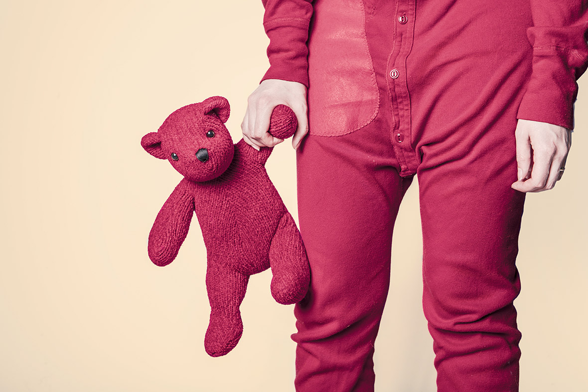 Person holding red teddy bear in hand.