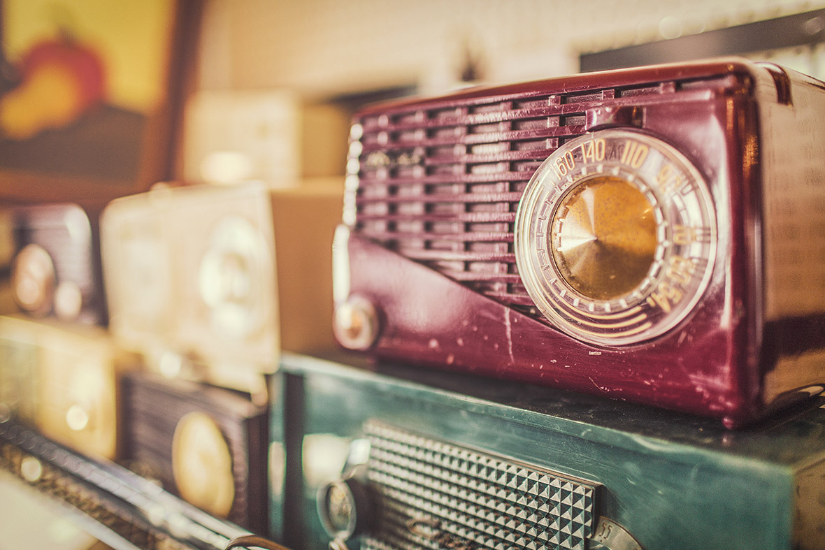 Vintage radios lined up on a shelf.