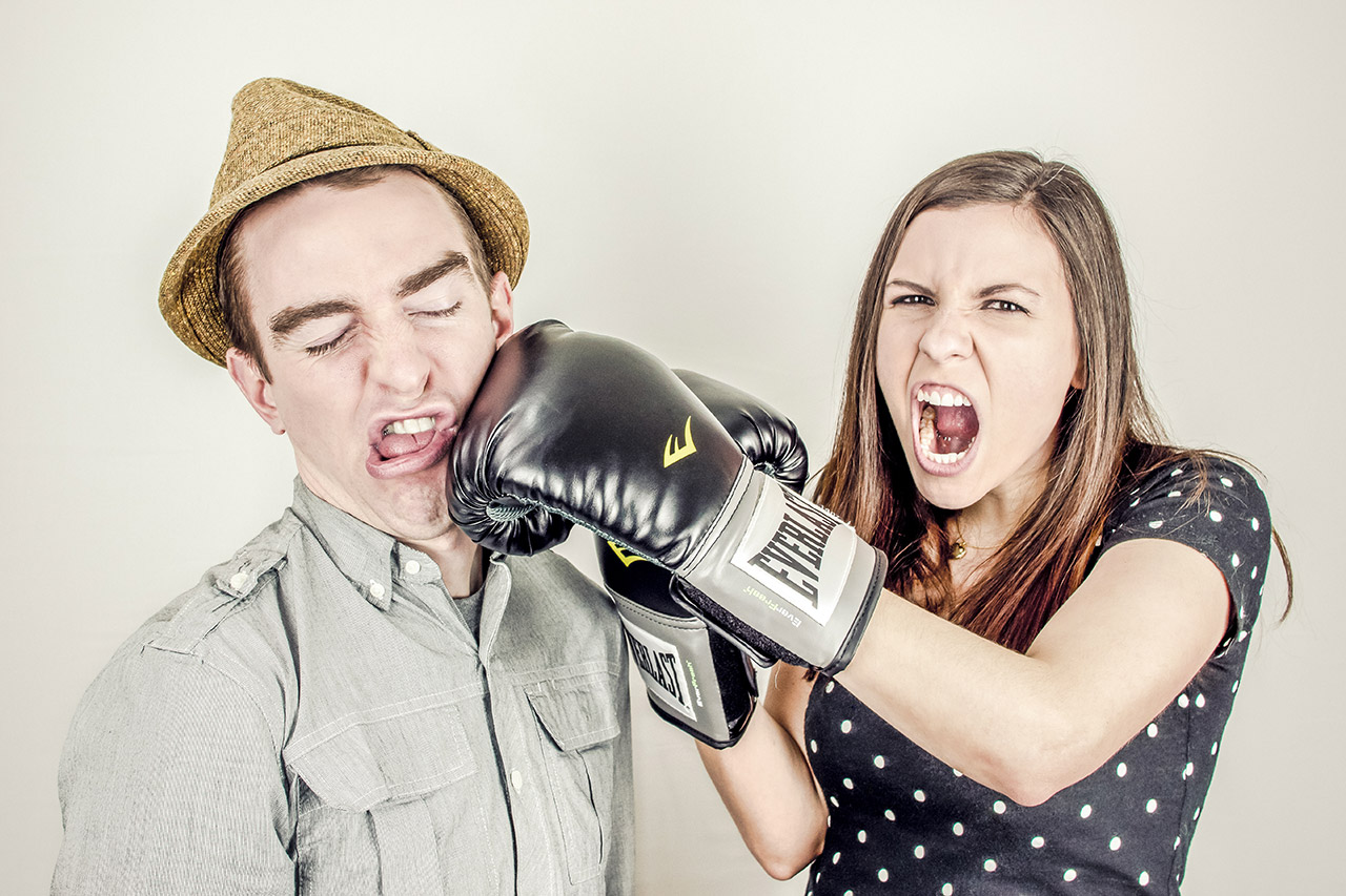 Woman punching man with boxing glove playfully.