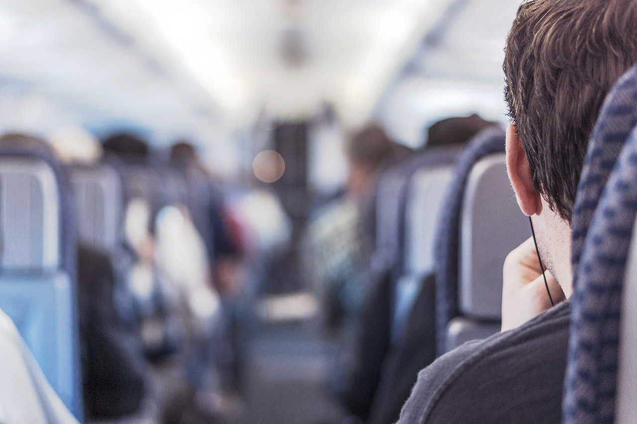 Inside a crowded airplane cabin, passengers seated.